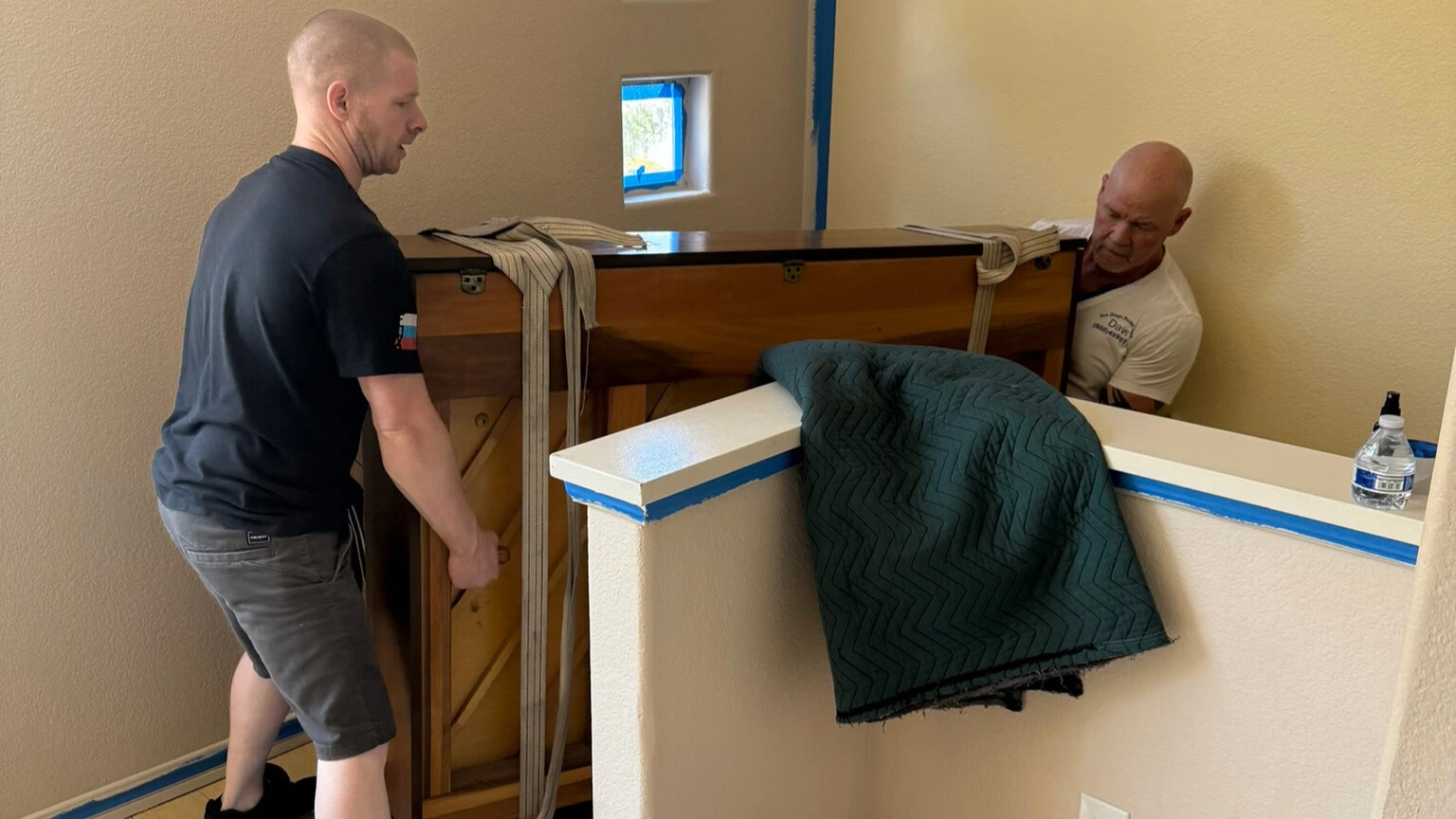 Professional movers handling a piano on stairs