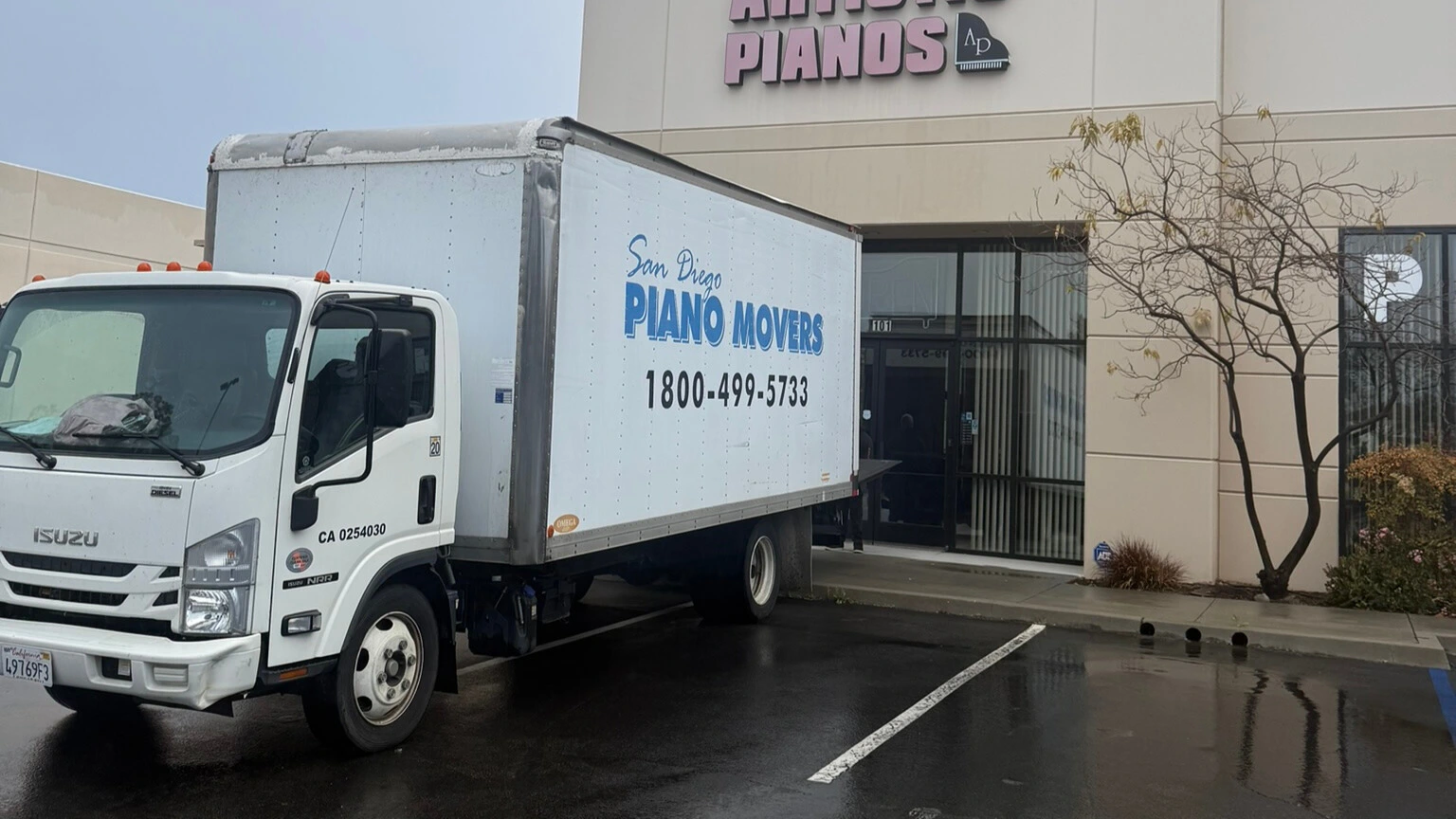 Professional piano movers carefully securing a grand piano in a moving truck